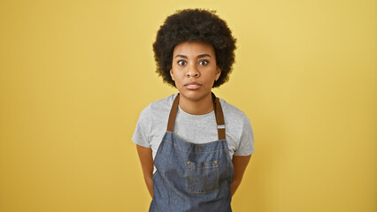Portrait of an adult african american woman with curly hair wearing an apron against a yellow...