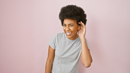 Smiling african american woman with curly hair against a pink isolated background, portraying positivity and beauty.