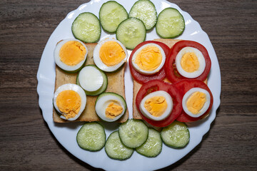 Toast bread with eggs, tomatoes and cucumber slices in a plate