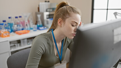 A focused young woman working on a computer in a laboratory setting, showcasing healthcare or scientific research ambiance.