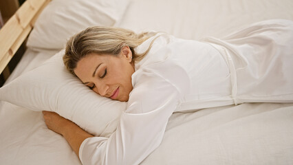 Young blonde woman lying on bed sleeping at bedroom