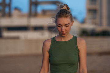 Contemplative Young Woman in Green Tank Top Outdoors