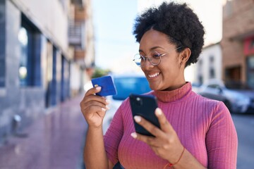 Fototapeta na wymiar African american woman using smartphone and credit card at street