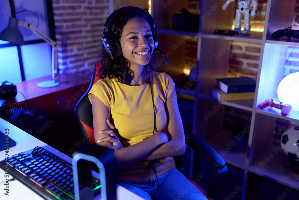 Sticker Young african american woman streamer smiling confident sitting with arms crossed gesture at gaming room