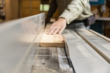 Horizontal photo woodworker carefully cutting on table saw. Business concept.