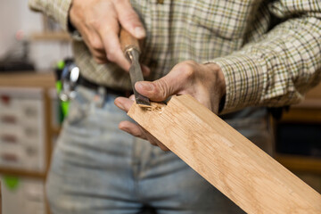 Horizontal photo carpenter hand-carving wood with chisel. Business concept.