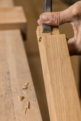 Vertical photo carpenter hand-carving a notch in wood with chisel. Copy space. Business concept.