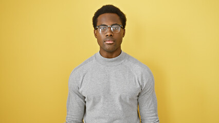 Portrait of a young african american man in glasses against a yellow background
