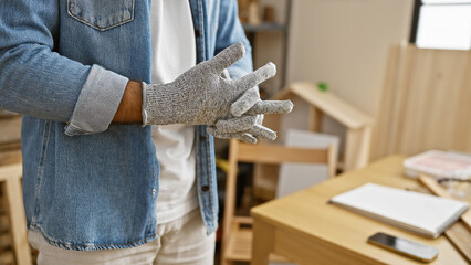 Crafty hands of a hispanic man, a glove-wearing carpenter immersed in woodwork at a professional carpentry workshop