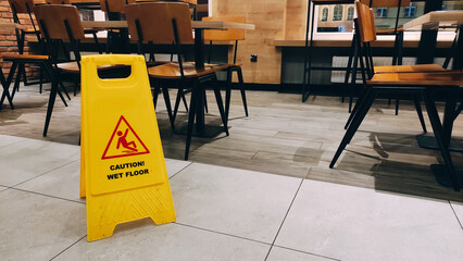 Signboard with caution wet floor of yellow color indoor the cafe