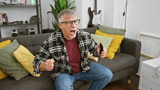 Surprised man watching television in a modern living room, expressing excitement