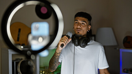 Smiling young latin man, a tattooed musician, singing his heart out and dancing in a dimly lit...
