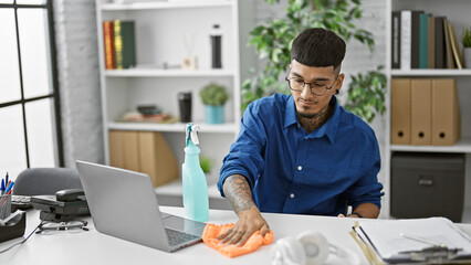 Passionate young latin business worker spructures up his office, serious man cleaning his desk with efficiency