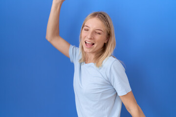 Young caucasian woman wearing casual blue t shirt dancing happy and cheerful, smiling moving casual and confident listening to music