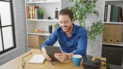 Young hispanic man business worker using touchpad smiling at the office