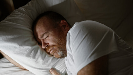 Handsome middle-aged caucasian man, comfortably resting in the cozy atmosphere of his bedroom,...
