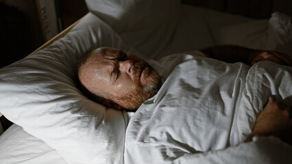 Handsome middle-aged caucasian man, comfortably resting in the cozy atmosphere of his bedroom, peacefully asleep engulfed in the soft morning light.