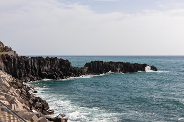 Unique rock formation of coastline of idyllic fishermen village Camara de Lobos on Madeira island, Portugal, Europe. Waves breaking on rocky coast of Atlantic Ocean. Calm tranquil atmosphere at sea