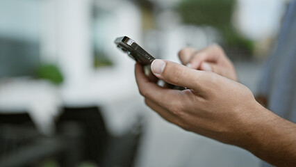 Downtown digital life, young urban man holds the world in his hand, engaging in a texting conversation using his smartphone on the city street.