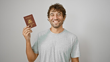 Cheerful young man joyfully flashing his philippine passport, standing confidently isolated against...