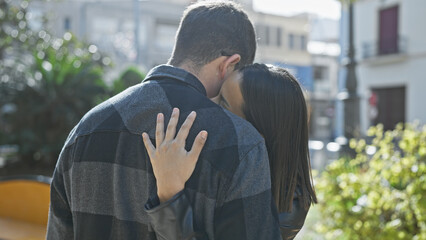 An affectionate couple embraces on a sunny urban street, capturing a moment of love and intimacy in...