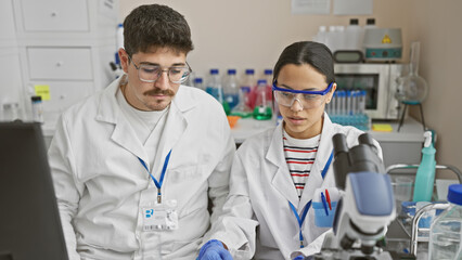 A man and woman in lab coats analyzing samples together in a scientific laboratory.