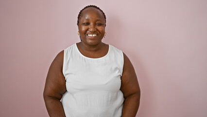 Confident african american woman smiling and standing over an isolated pink background