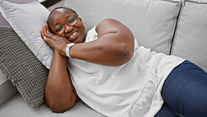 Joyful plus size african american woman, confident and happy, resting comfortably on her living...