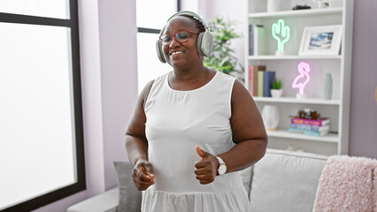 Cheerful african american woman groovin' at home, rocking her braids, confidently enjoying music...