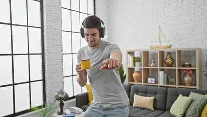 Young hispanic man enjoying music with headphones and coffee in a cozy living room.