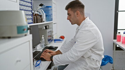Naklejka na ściany i meble Young, handsome hispanic scientist engrossed in intensive medical research, using computer analysis in a professional lab environment