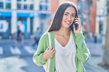 Fototapeta premium Young beautiful hispanic woman smiling confident talking on the smartphone at street