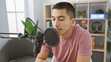 Hispanic man speaking into microphone in radio studio