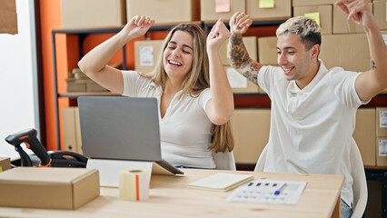 Two workers man and woman using laptop celebrating at office