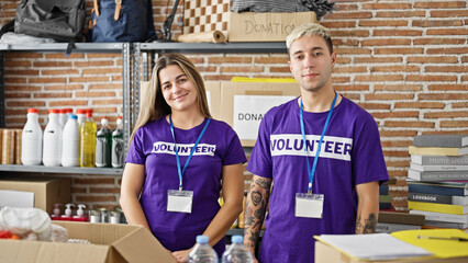 Man and woman volunteers smiling confident smiling at charity center