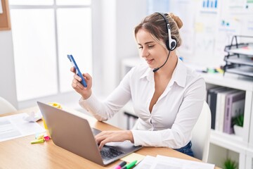 Young blonde woman call center agent holding using smartphone working at office