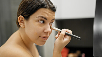 Young beautiful hispanic woman applying make up in the bathroom