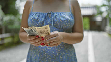 Young woman's hands, busy counting yen banknotes in the traditional streets of kyoto, a caucasian...
