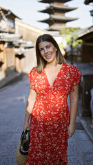 Beautiful hispanic woman smiling joyfully, confidently posing, standing on the old traditional streets of gion, kyoto, her sunny, carefree nature shining through for a fun-filled japan adventure.