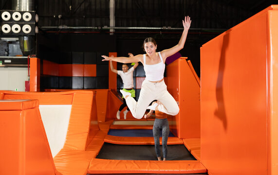 Expressive cheerful young girl enjoying jumping in indoor trampoline arena. Funny active leisure concept ..