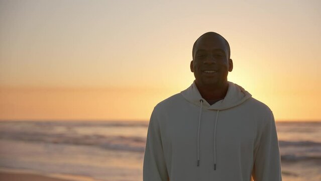 Casually dressed young man with eyes closed enjoying peace and beauty of beautiful sunrise morning over beach and sea in South Africa - shot in slow motion