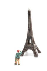 miniature figurine of an hiker looking at Eiffel Tower in Paris on a white background