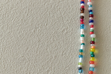 close-up overhead view of a necklace with multicolored beads on a white surface
