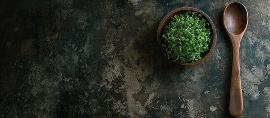 A wooden spoon rests beside a wooden bowl overflowing with vibrant green grass. The contrast between the natural elements creates an intriguing composition.