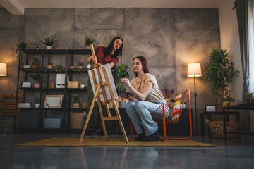 Fototapeta na wymiar two young women paint at home mentor artist help to create art