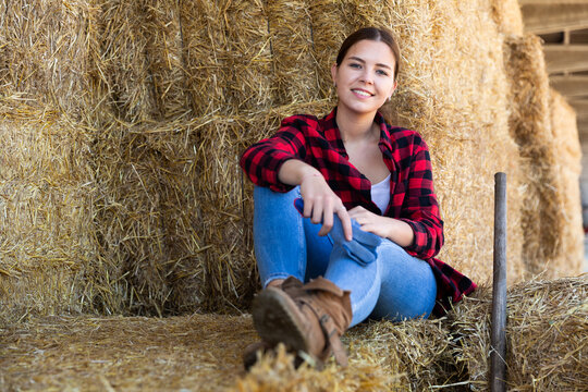 Portrait of smiling young woman farmer posing at hay storage on dairy farm