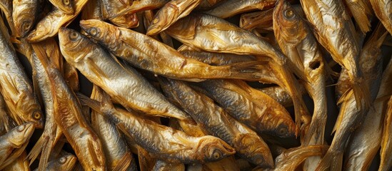 A group of dried fish arranged in a pile next to each other, possibly undergoing the sun-drying process. The fish appear to be well-preserved, with a desirable level of saltiness and moisture.