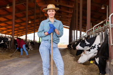 Portrait of positive female farm worker in a cowshed