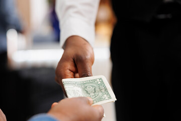 Close up of hospitality worker accepting of cash payment, taking money from customer. Hotel guest...