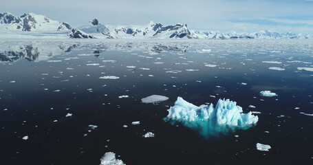 Melting iceberg drift in open Antarctica ocean. Arctic winter landscape at global warming problem. Polar climate change at sunny winter day. Cinematic ecology scene. Aerial drone flight